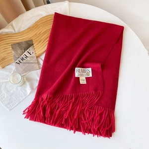 Vue détaillée de l'écharpe en cachemire rouge avec glands et étiquette sur une table blanche