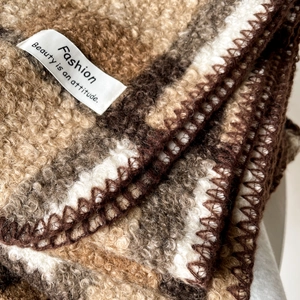 Nahaufnahme eines dicken Karo-Strickschals mit braun-weißem Bouclé-Wollstoff-Detail