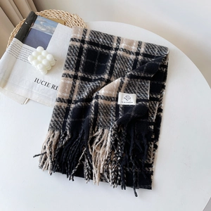 Detail of checkered bouclé knit scarf with fringe and brand label on a stylish table