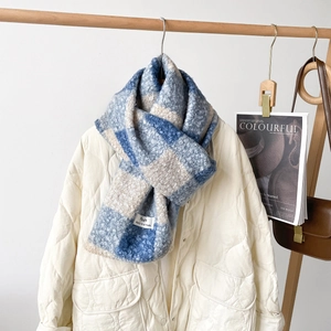 Detail eines blau-weiß karierten Strickschals mit dicker Vliesstruktur und Fransen