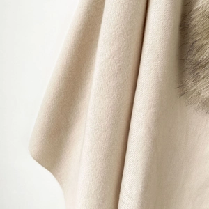 Close-up of beige cashmere shawl showing luxury fox fur collar and twill texture
