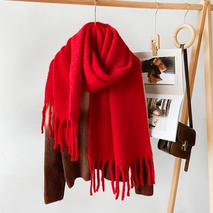 Detail of red mohair scarf with tassels showing thick fuzzy texture on a wooden hanger