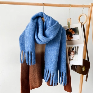 Detail shot of bright blue knit scarf with long tassels on a wooden hanger with magazine