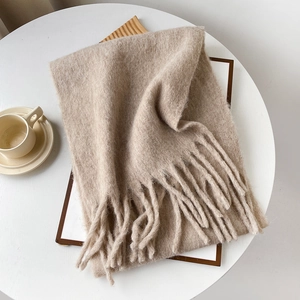 Detailed close-up of beige mohair scarf texture with elegant long fringe tassels