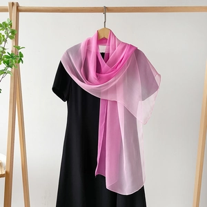 Nahaufnahme von rosa Chiffon-Schal mit Farbverlauf an einem Holzkleiderbügel