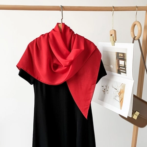 Detail eines eleganten roten Chiffon-Schals, der über ein schwarzes T-Shirt fällt