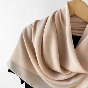 Detailstruktur eines leichten beige Schals aus Chiffon an einem Holzbügel