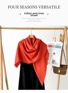 Detail of orange cotton linen scarf with frayed edges hanging on a wooden hanger