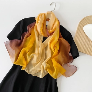 Detailansicht eines Chiffonschals mit gelb-braunem Farbverlauf auf einem Kleiderbügel aus Holz