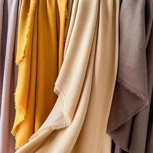 Close-up of soft cotton-linen scarves featuring fringe edges and various solid colors