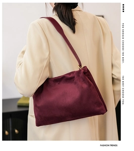 Detail view of burgundy velvet Boston bag featuring gold metal buckles and soft texture
