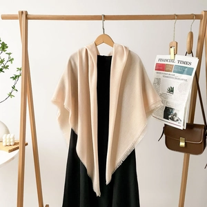 Detail of soft beige cotton-linen blend shawl featuring elegant fringe and minimalist style