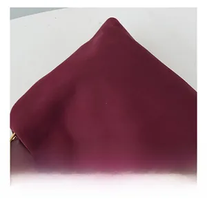 Detail view of burgundy suede fabric texture with elegant gold metal hardware accents