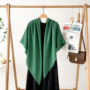 Detail of forest green pashmina shawl with tassel fringe draped over a black dress