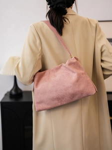Detailed view of pink suede Boston bag on shoulder in a minimalist indoor setting