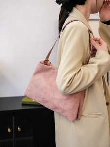 Detail of dusty pink suede Boston bag featuring matte texture and slim leather strap