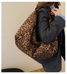 Detailed close-up of a large leopard print hobo bag worn over the shoulder by a model
