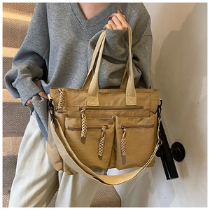 Detail of khaki nylon multi-pocket tote bag with woven rope zipper pulls on long strap