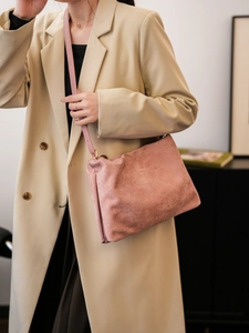 Close-up of pink suede Boston bag with gold hardware worn over a khaki trench coat