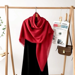 Detail of red oversized shawl with fringe edges styled with a black dress and newspaper