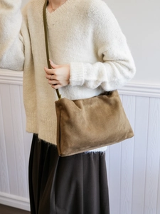 Detailed view of brown suede Boston bag styled with elegant beige knitwear and skirt