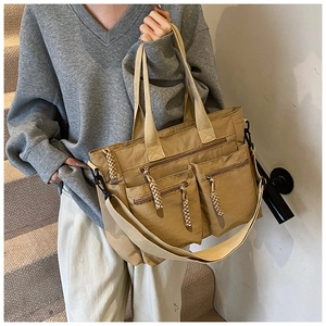 Close-up of khaki multi-pocket tote bag with woven zipper pullers and adjustable strap