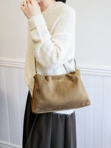 Detail of a brown suede Boston bag featuring minimalist texture and sleek shoulder strap