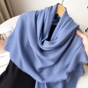 Detailed texture of dusty blue pashmina scarf with fine fringe on a wooden hanger
