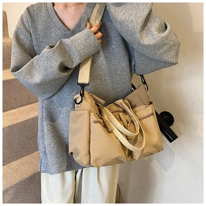 Detail of khaki multi-pocket tote bag with wide adjustable shoulder strap and durable zippers