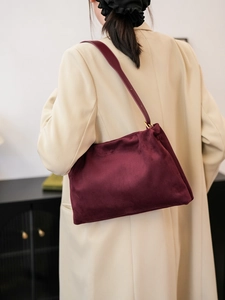 Detail of burgundy velvet shoulder bag with elegant pleated design and gold buckle