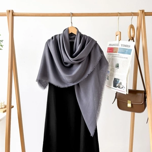 Detail of grey linen-feel shawl showcasing delicate fringe edges and soft drape
