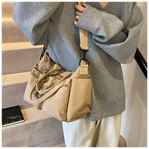 Detail of khaki nylon multi-pocket tote bag with adjustable straps and utility design