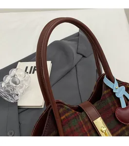 Détail d'un sac cabas rétro à carreaux avec fermoir rotatif doré et breloque cerise