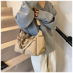 Detail showing khaki multi-pocket canvas tote bag with woven zipper pulls and metal clips