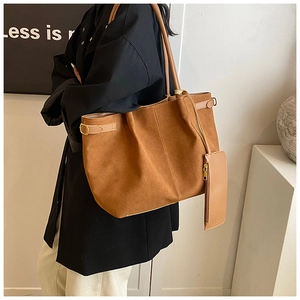 Detail van grote bruine suède shopper met zijgespen en bijpassend ritsvakje aan de tas