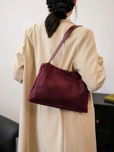 Close-up of burgundy suede Boston bag worn with a beige oversized blazer