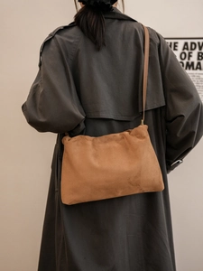 Detailed view of a brown suede Boston bag styled with a minimalist leather shoulder strap