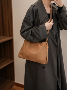 Caramel suede Boston bag with gold buckle detail worn with a dark grey trench coat