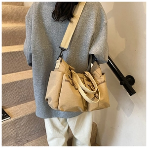 Detail of khaki nylon tote bag showing multiple functional pockets and wide strap
