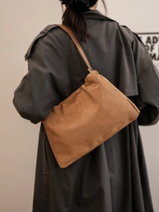 Macro detail of brown suede Boston bag with soft pleats and gold hardware on shoulder