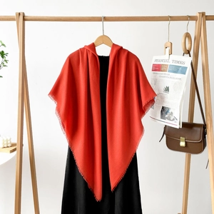 Detail of red hooded shawl with frayed edges and fringe in elegant cashmere-like texture