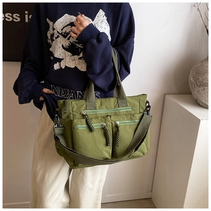 Detail shot of matcha green multi-pocket nylon tote bag with stylish braided zipper pulls