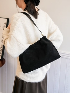 Close-up of black suede pleated cloud bag with elegant gold metal ring and strap detail