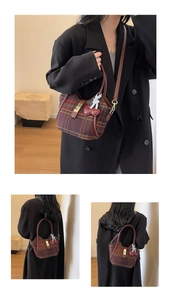 Détail du sac cabas en laine à carreaux avec poignées en cuir et breloque cerise