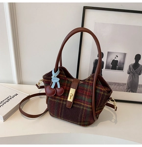 Détail du sac cabas en laine à carreaux vintage avec poignée en cuir brun et cerise