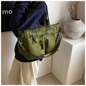 Detail view of army green multi-pocket nylon tote bag with braided zipper pulls