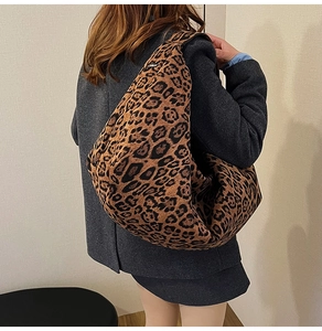 Detailed side view of large leopard print hobo bag in suede material with wide shoulder strap