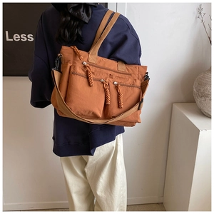 Detail view of caramel nylon tote bag with three front zip pockets and wide shoulder strap