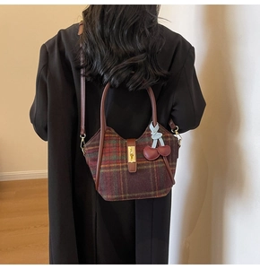 Détail du sac cabas en laine à carreaux avec poignées en cuir et breloque cerise rouge