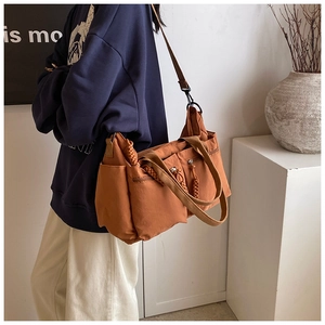 Detail view of caramel orange multi-pocket tote bag with woven zipper pullers